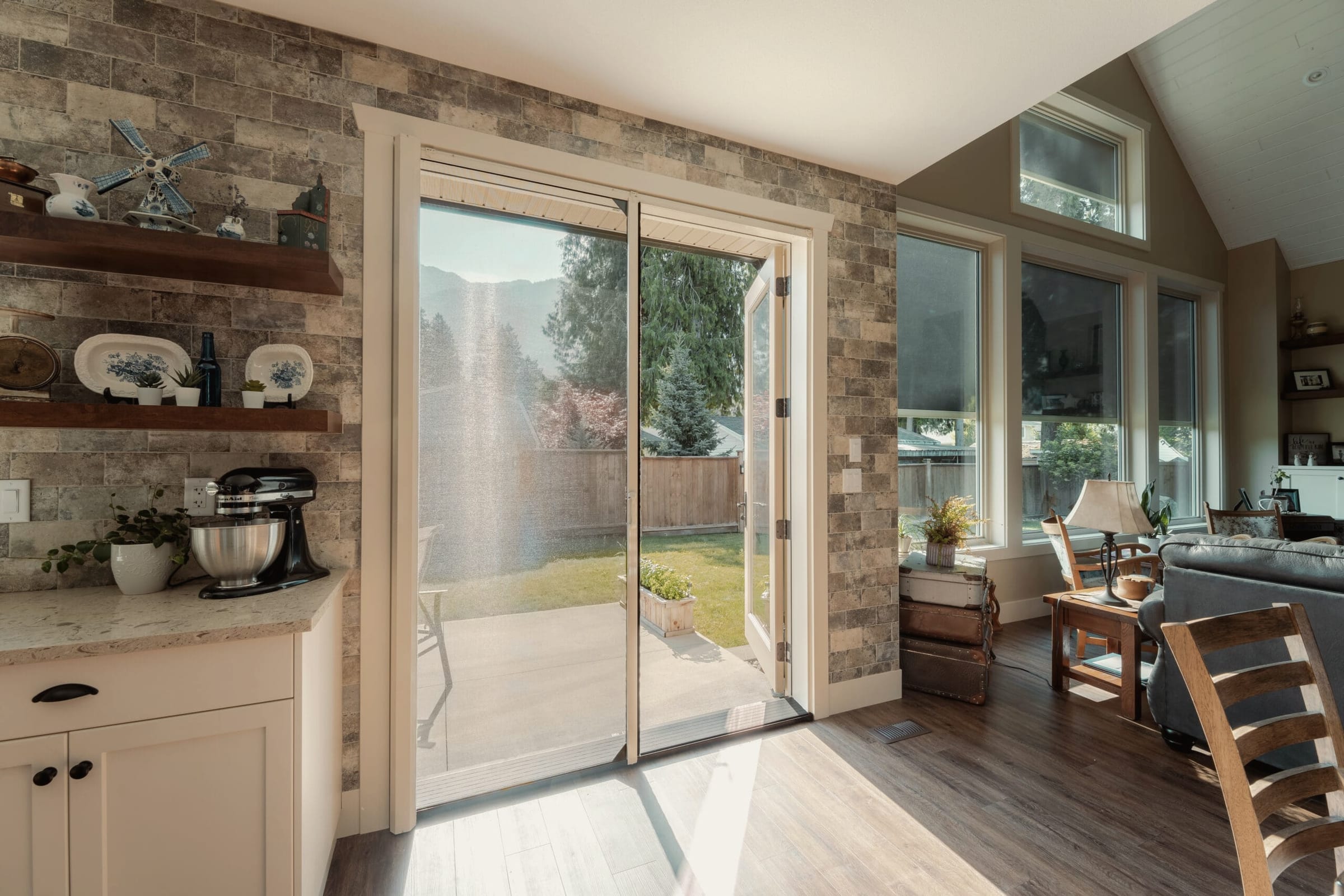 A retractable screen pulled partway across a sliding glass door in a bright living room, looking out to a fenced yard.