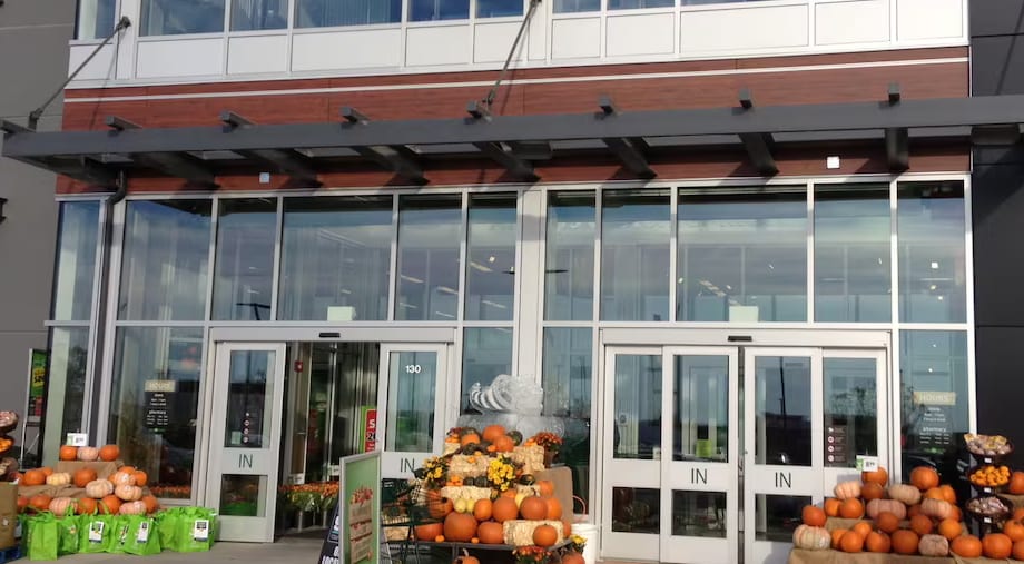 A glass storefront entrance: a two-storey curtain wall of glass over a row of four automatic sliding doors.